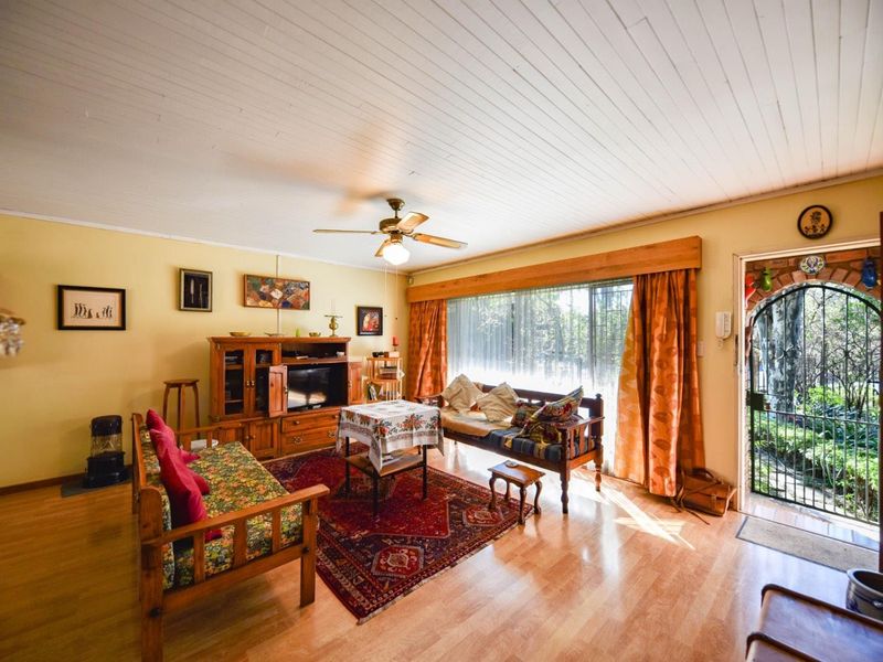 A living room featuring laminate flooring, a timber-paneled ceiling, a ceiling fan, and direct access to an outdoor area through a security gate.
