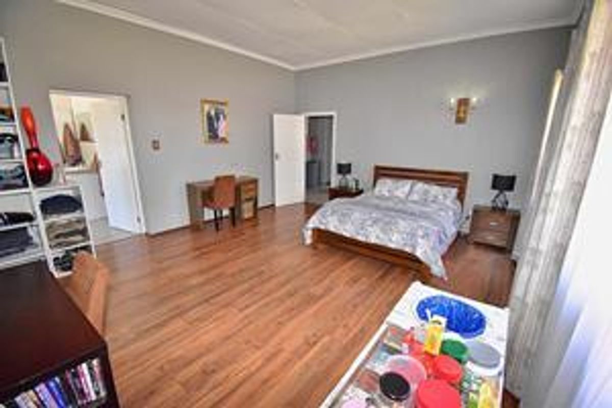 Spacious bedroom featuring wood-look laminate flooring, neutral wall finishes, and direct access to adjacent rooms.