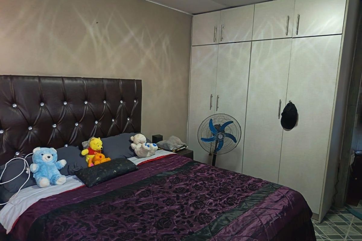 A bedroom featuring a large built-in wardrobe with ample storage and tiled flooring.