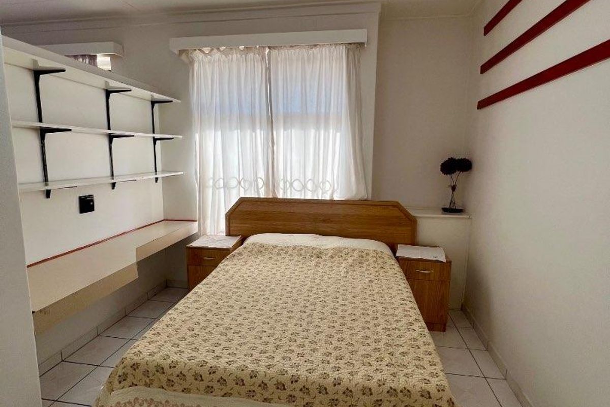 A bedroom featuring tiled flooring, built-in shelving, and a built-in desk area, offering a functional layout with neutral finishes.