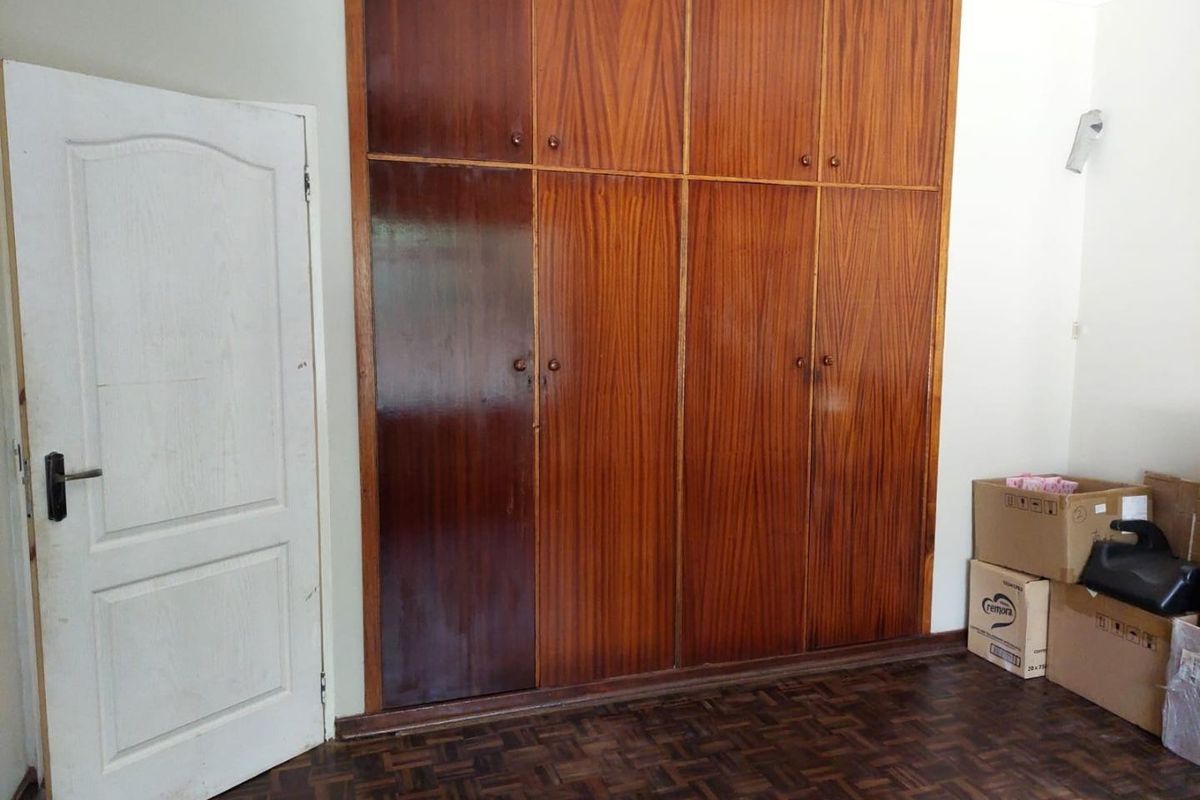 A bedroom featuring classic parquet flooring and extensive floor-to-ceiling built-in wooden cupboards providing ample storage space.