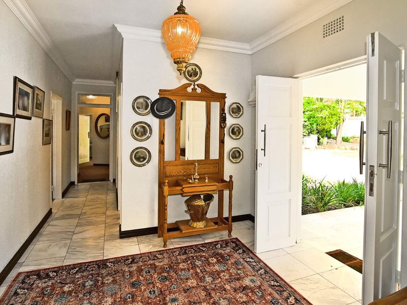 Welcoming entrance hall featuring polished marble flooring, decorative cornice, and a bright, open transition to the exterior garden area.