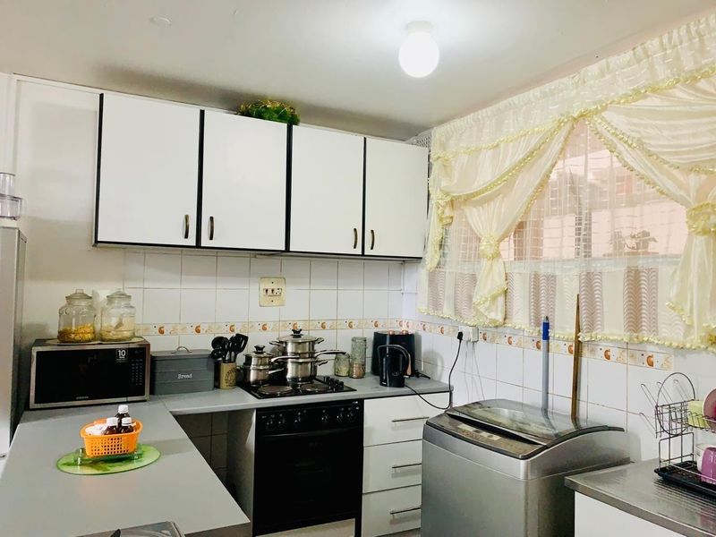 A functional kitchen featuring white cabinetry, tiled backsplash, built-in oven, and hob, providing a practical workspace for daily cooking and laundry needs.