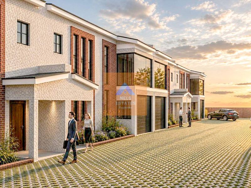 A modern townhouse complex featuring a brick facade, large windows, and a paved driveway, showcasing contemporary architectural design.