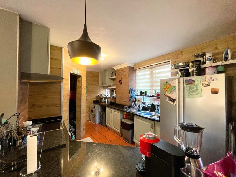 A functional kitchen featuring granite countertops, wood-paneled walls, tiled flooring, and built-in cabinetry with an integrated extractor fan.