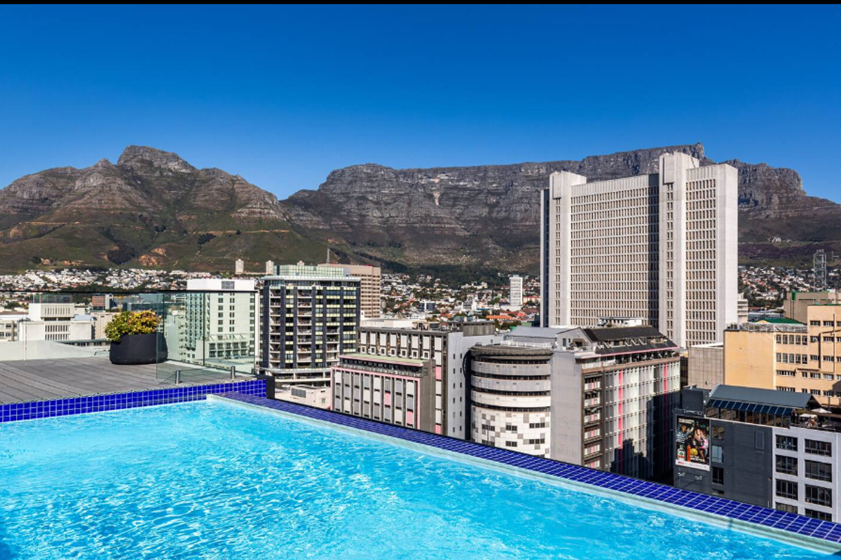 A stunning rooftop infinity pool featuring a glass balustrade and panoramic views of the city and Table Mountain.