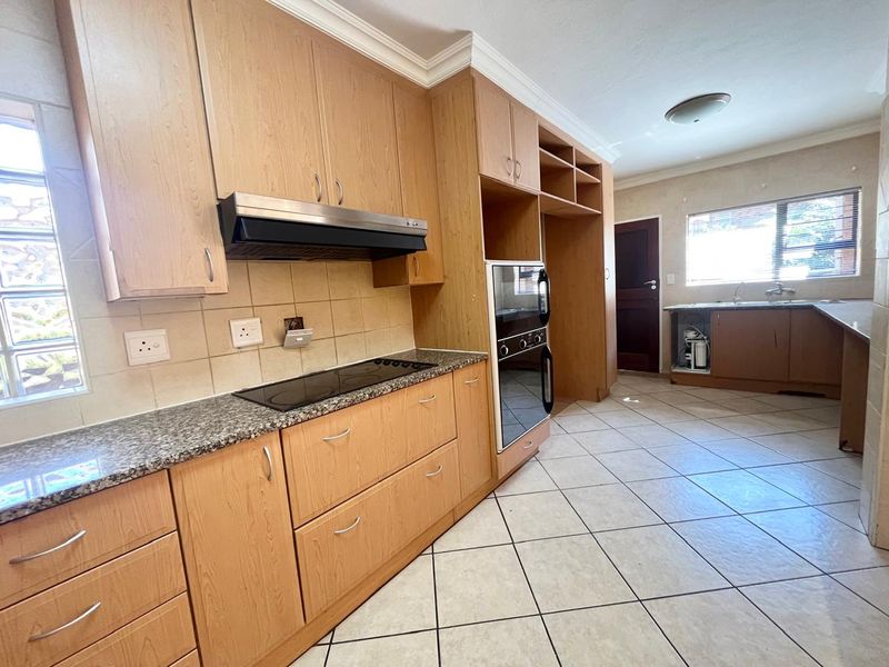 Spacious kitchen featuring light wood cabinetry, granite countertops, built-in oven and hob, and tiled flooring. Requires minor repairs to the under-sink cabinetry.
