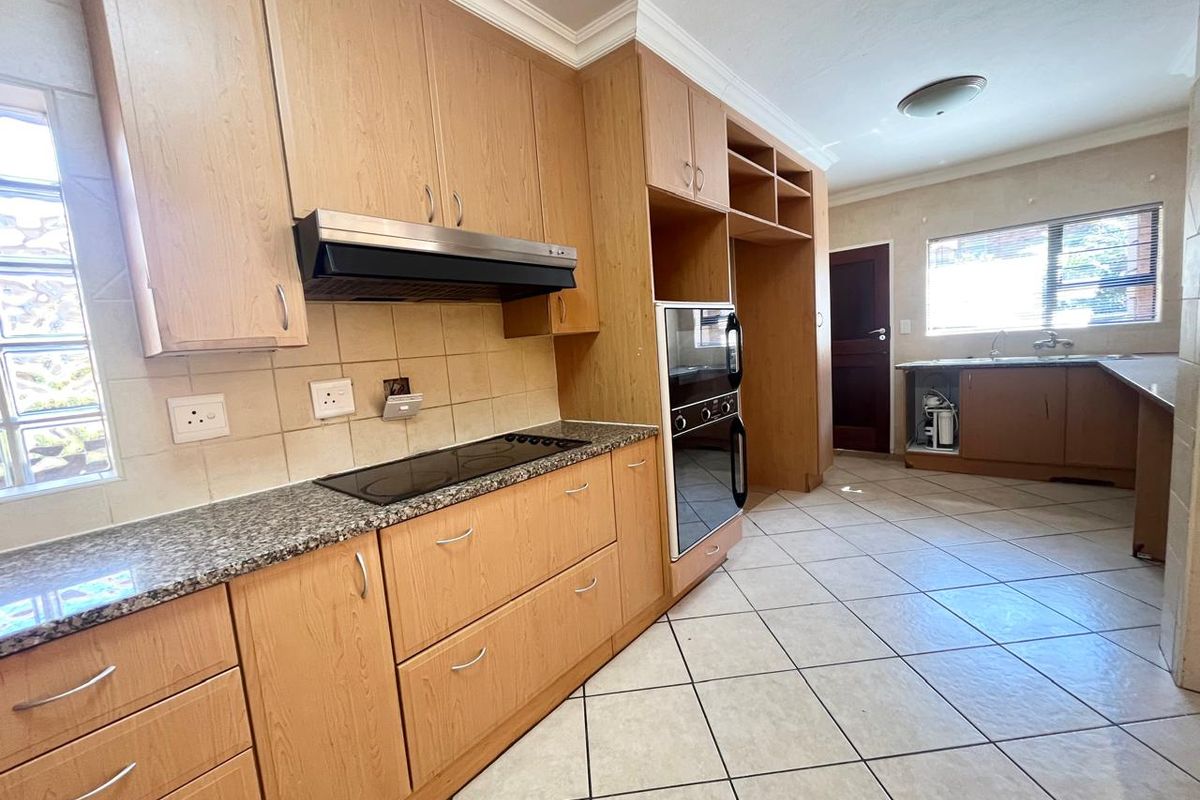 Spacious kitchen featuring light wood cabinetry, granite countertops, built-in oven and hob, and tiled flooring. Requires minor repairs to the under-sink cabinetry.