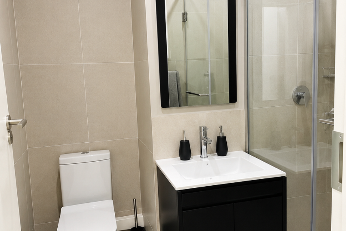 Modern bathroom featuring a wall-mounted vanity, glass-enclosed shower, and neutral floor-to-ceiling tiling.