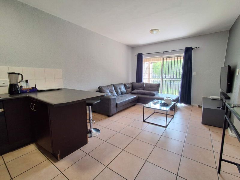 Open-plan living area featuring tiled flooring, a kitchen breakfast bar, and a sliding glass door leading to an outdoor space.