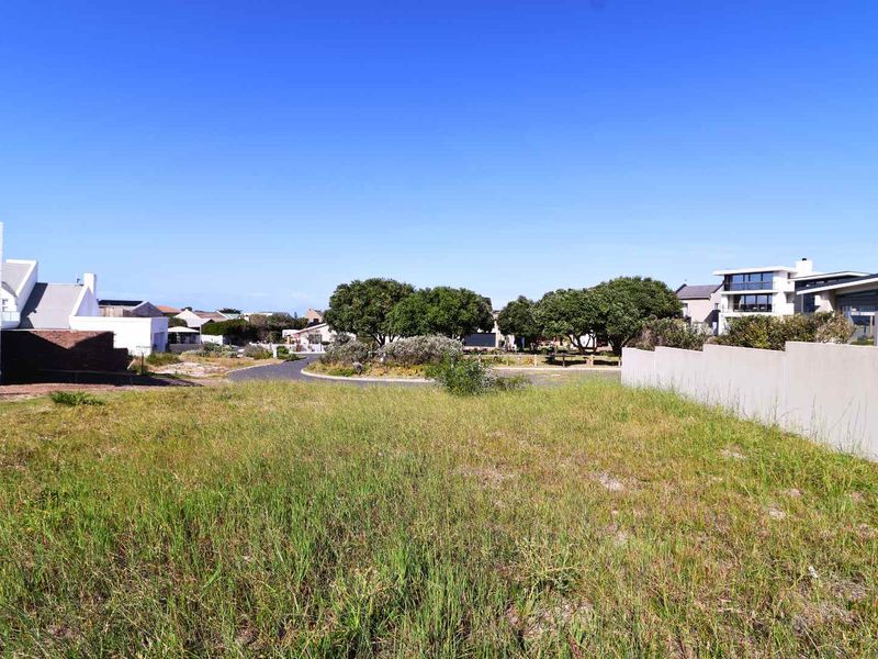 A vacant residential plot featuring established boundary walls and direct access to a paved street in a developed neighborhood.