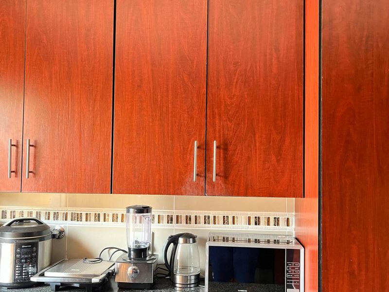 A kitchen area featuring wood-look laminate cabinetry, a tiled backsplash, and dark granite countertops.