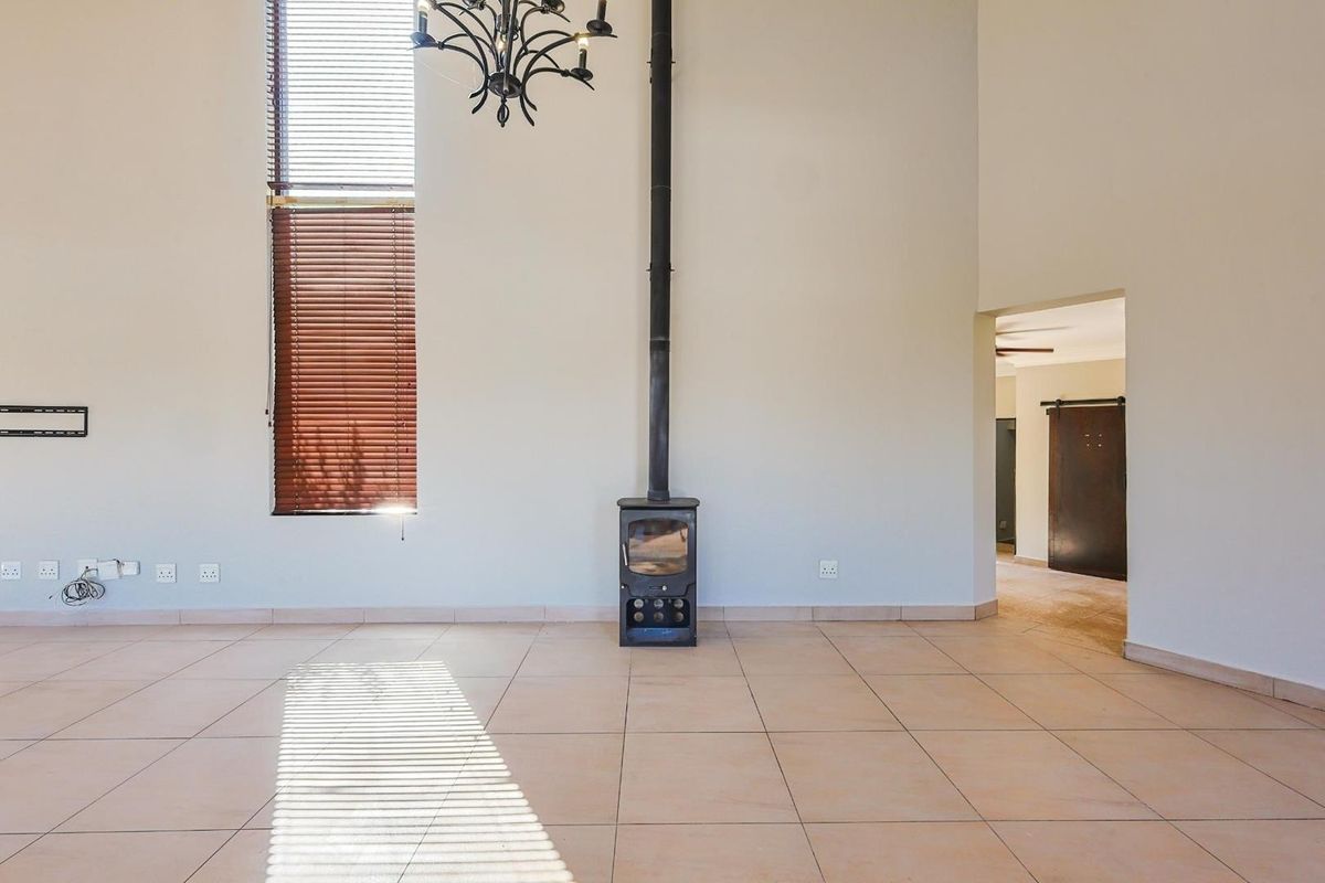 Spacious living area featuring high ceilings, tiled flooring, and a central freestanding fireplace, offering a bright and open layout.