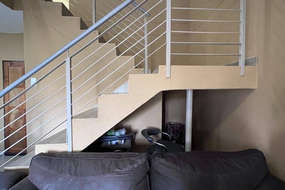 Interior view of a living area featuring a prominent staircase with modern metal railings and a neutral wall finish.