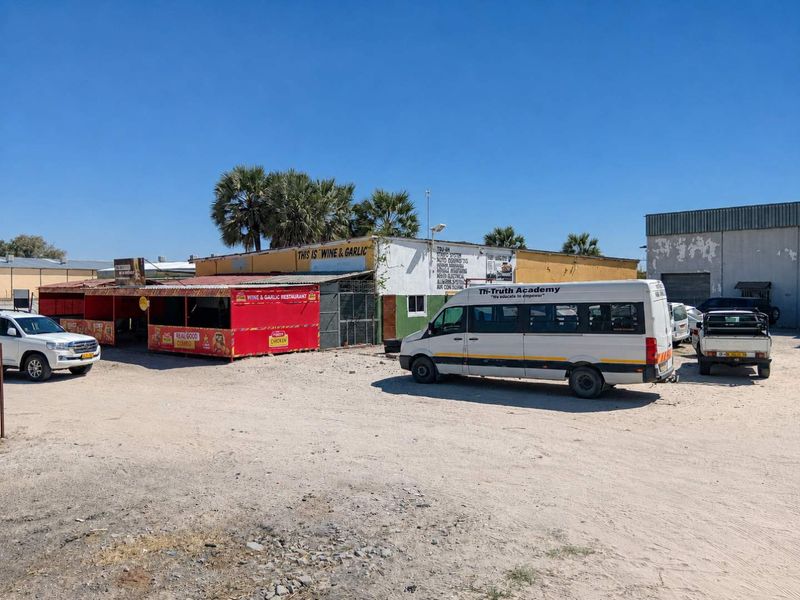 Front exterior view of a commercial property featuring a weathered facade, metal roofing, and an unpaved parking area.