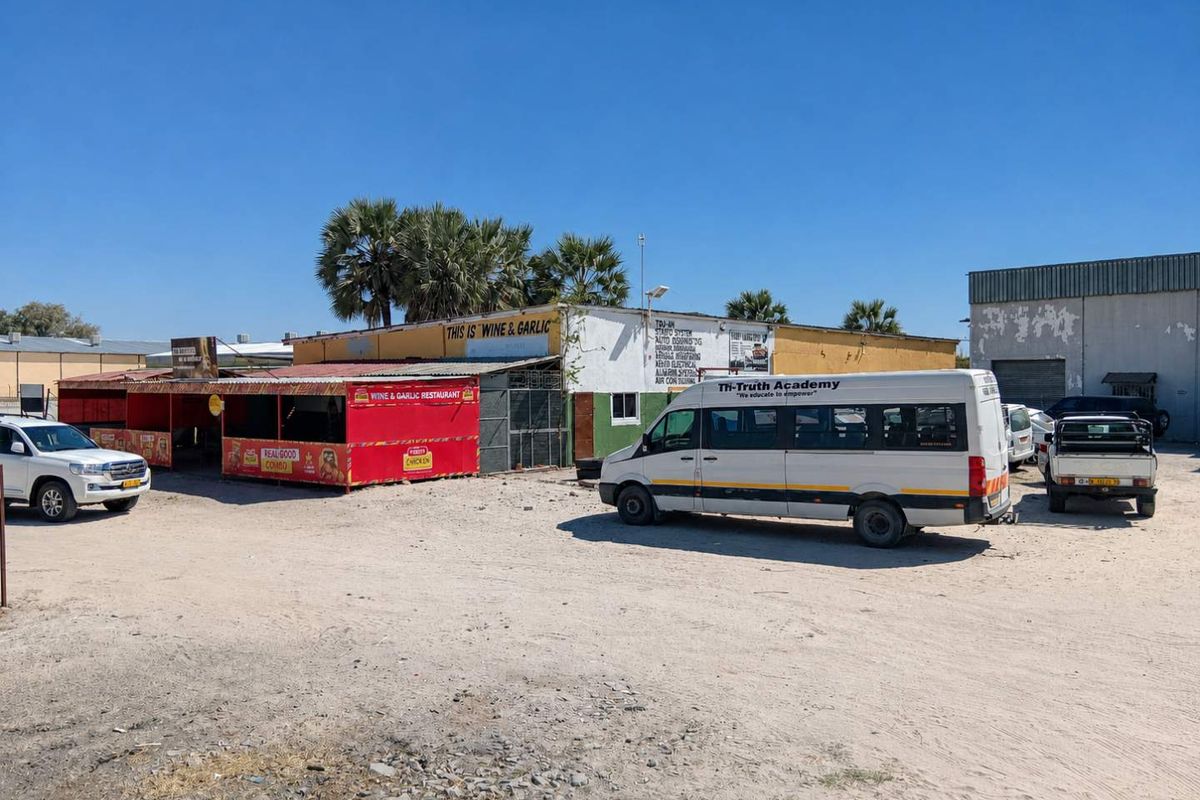 Front exterior view of a commercial property featuring a weathered facade, metal roofing, and an unpaved parking area.