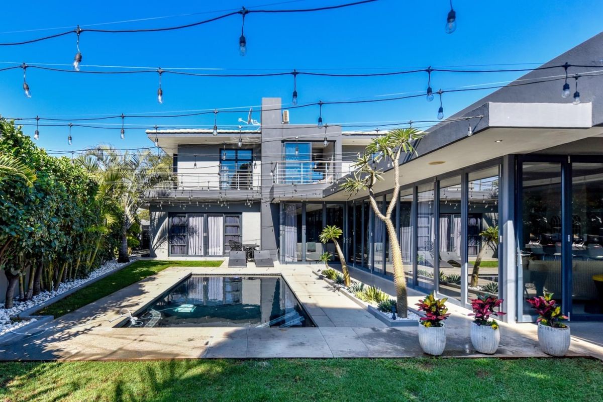 Modern rear exterior featuring a swimming pool, paved patio area, and large glass sliding doors connecting the indoor and outdoor living spaces.