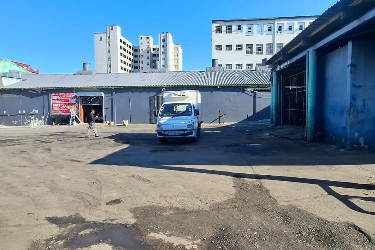 Industrial rear yard area featuring concrete paving, corrugated metal roofing, and access to warehouse or workshop units.