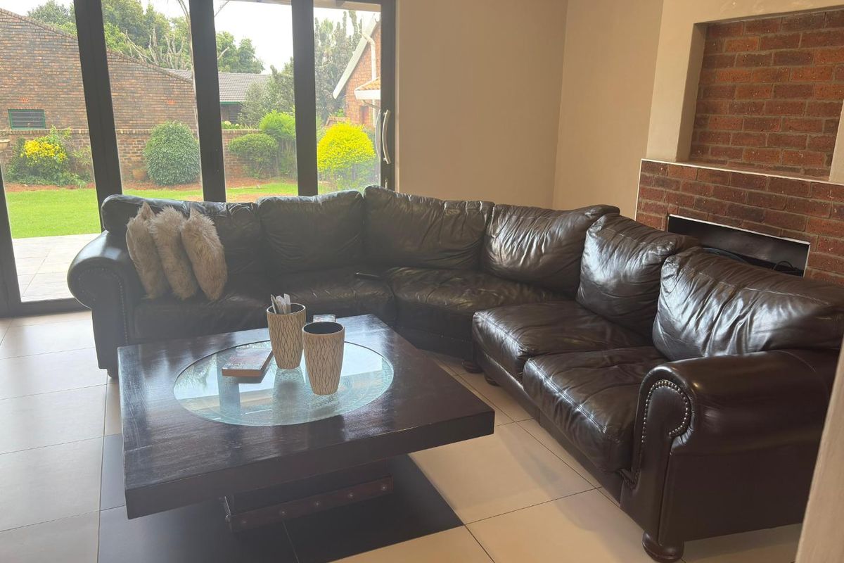 Spacious living room featuring large black-framed glass sliding doors leading to the garden and a built-in brick fireplace.