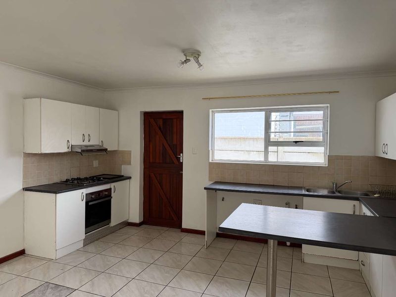 A functional kitchen featuring white cabinetry, gas hob, built-in oven, and tiled flooring, offering a blank canvas for modern updates.