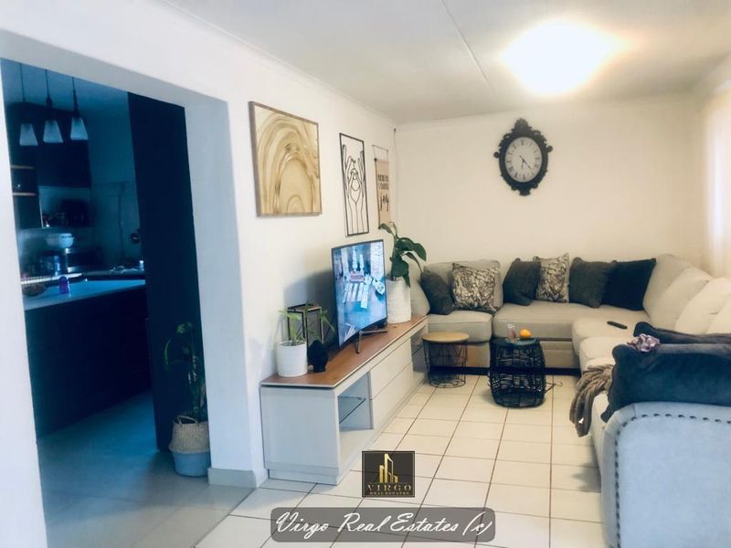 Open-plan living area featuring tiled flooring and neutral walls, seamlessly connecting to the adjacent kitchen space.
