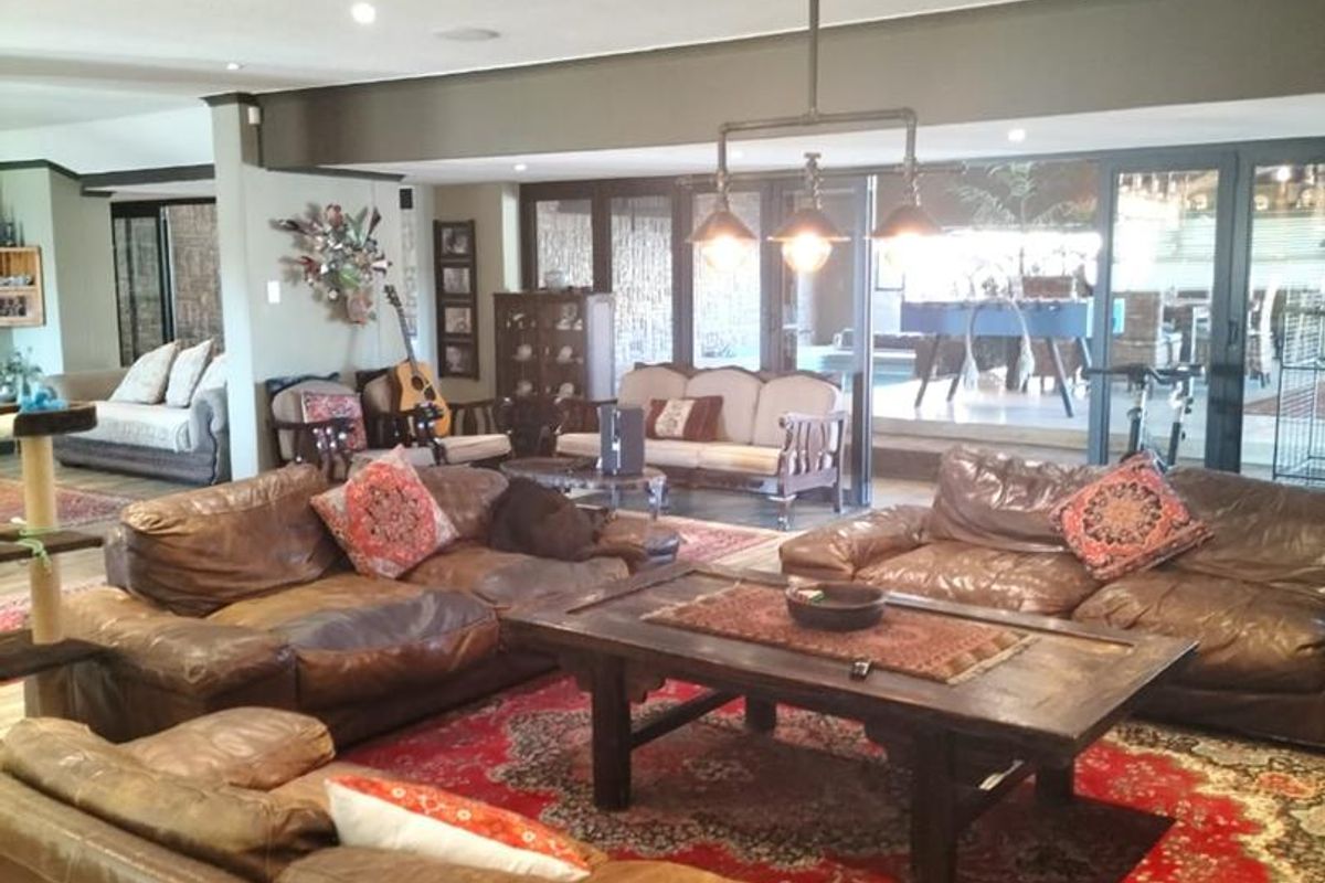 Spacious living room featuring recessed lighting, industrial pendant fixtures, and large sliding glass doors that provide seamless access to the outdoor patio area.