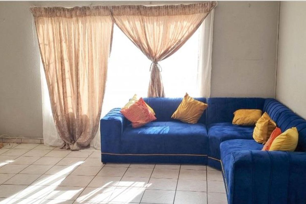 A living room featuring tiled flooring and large sliding glass doors that provide natural light.