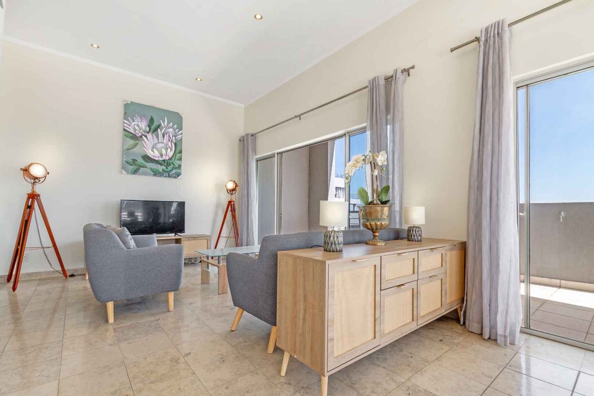 Bright and spacious living area featuring large sliding glass doors that open onto a private balcony, complemented by neutral tiled flooring throughout.