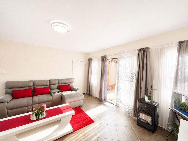 A bright living room featuring tiled flooring and a sliding glass door providing access to an outdoor patio area.