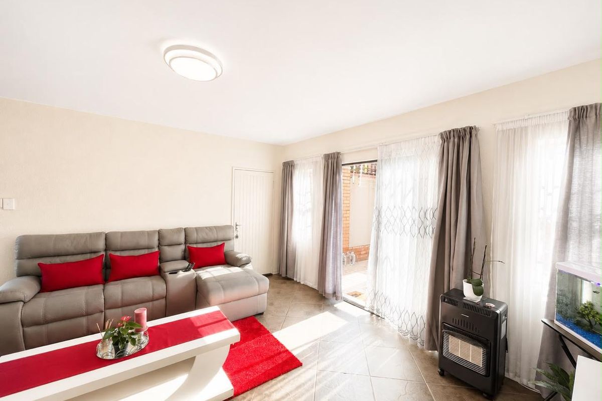 A bright living room featuring tiled flooring and a sliding glass door providing access to an outdoor patio area.