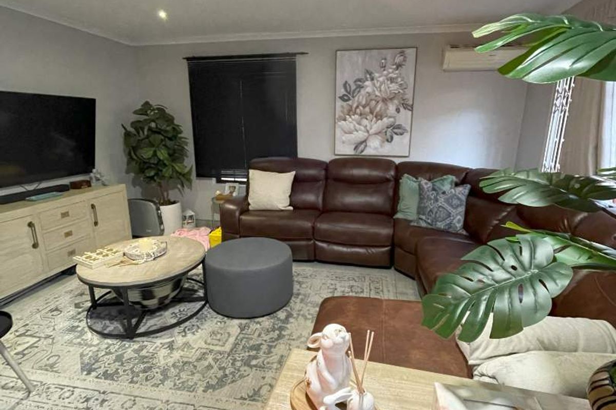 A comfortable living room featuring tiled flooring, recessed downlighting, and a wall-mounted air conditioning unit.