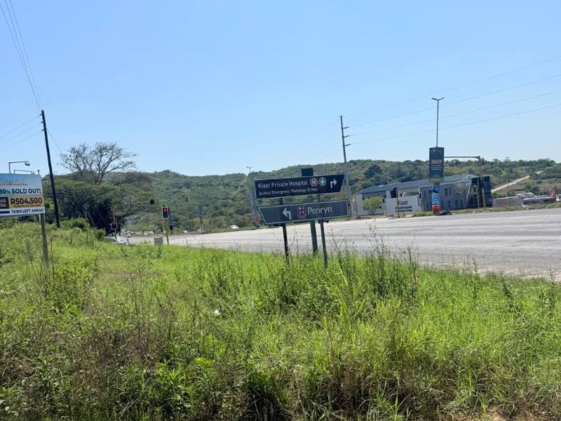 A street-level view of the vacant land showing proximity to local infrastructure, main roads, and nearby signage.