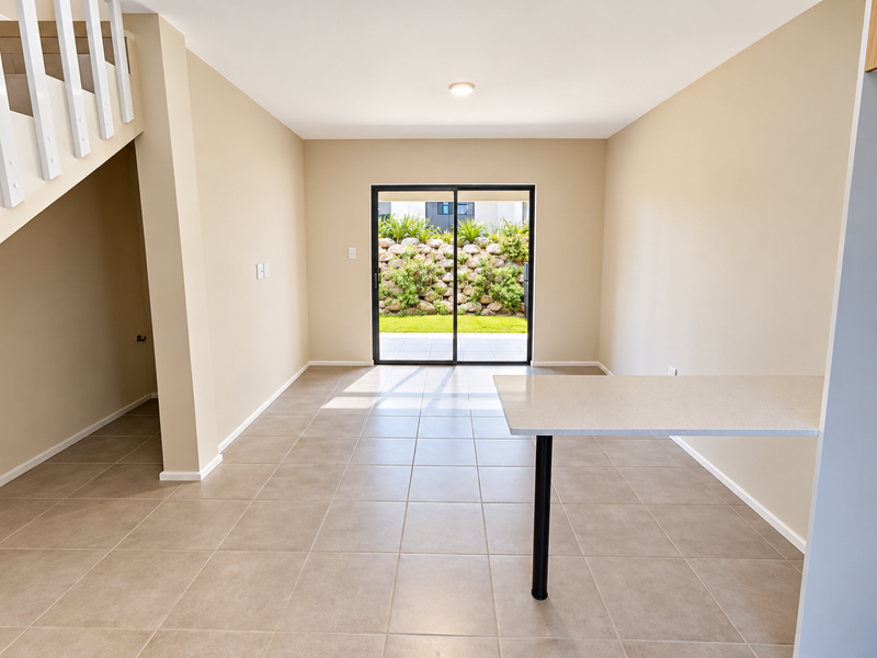 Bright open-plan living area featuring tiled flooring, a breakfast bar, and direct access to the rear garden through sliding glass doors.
