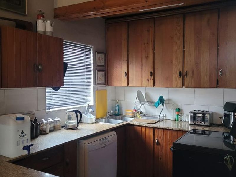 A functional kitchen featuring wooden cabinetry, granite countertops, and a tiled backsplash, offering a classic layout with potential for modern updates.