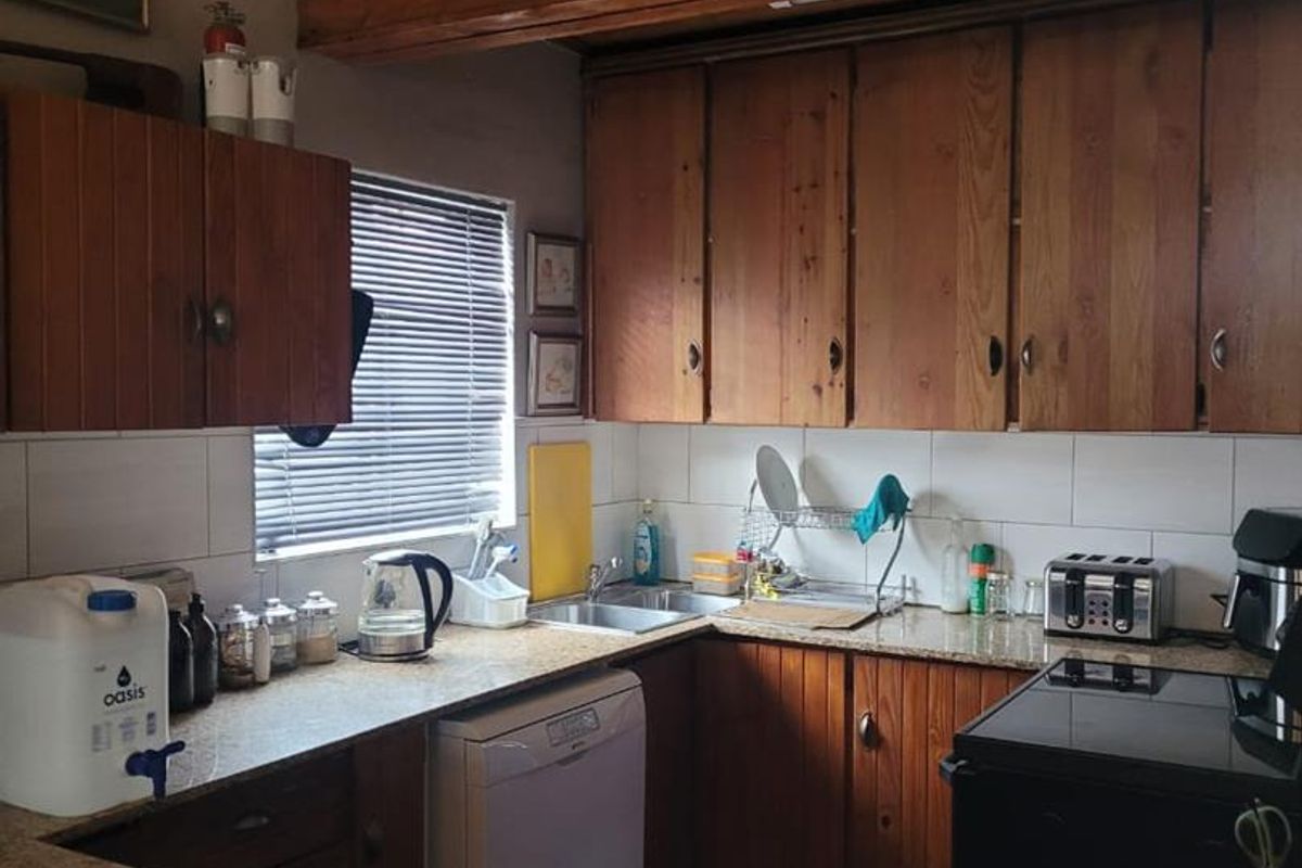 A functional kitchen featuring wooden cabinetry, granite countertops, and a tiled backsplash, offering a classic layout with potential for modern updates.