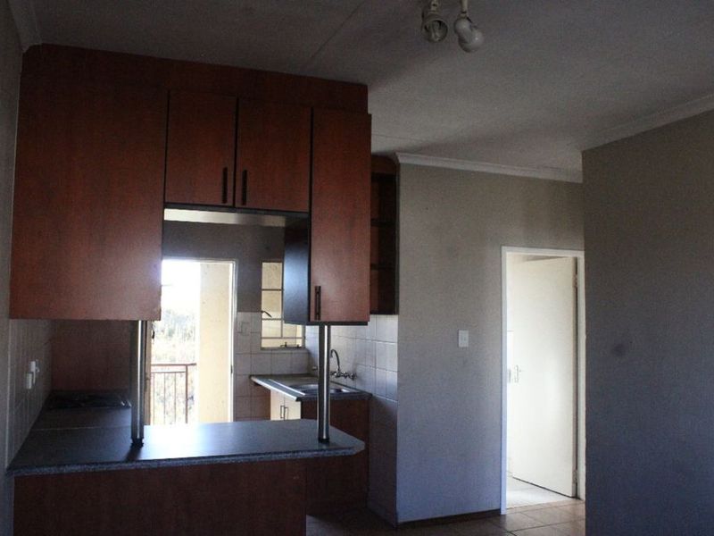 A dated kitchen featuring built-in cabinetry, a breakfast bar, and a tiled backsplash, offering a functional layout ready for modernization.