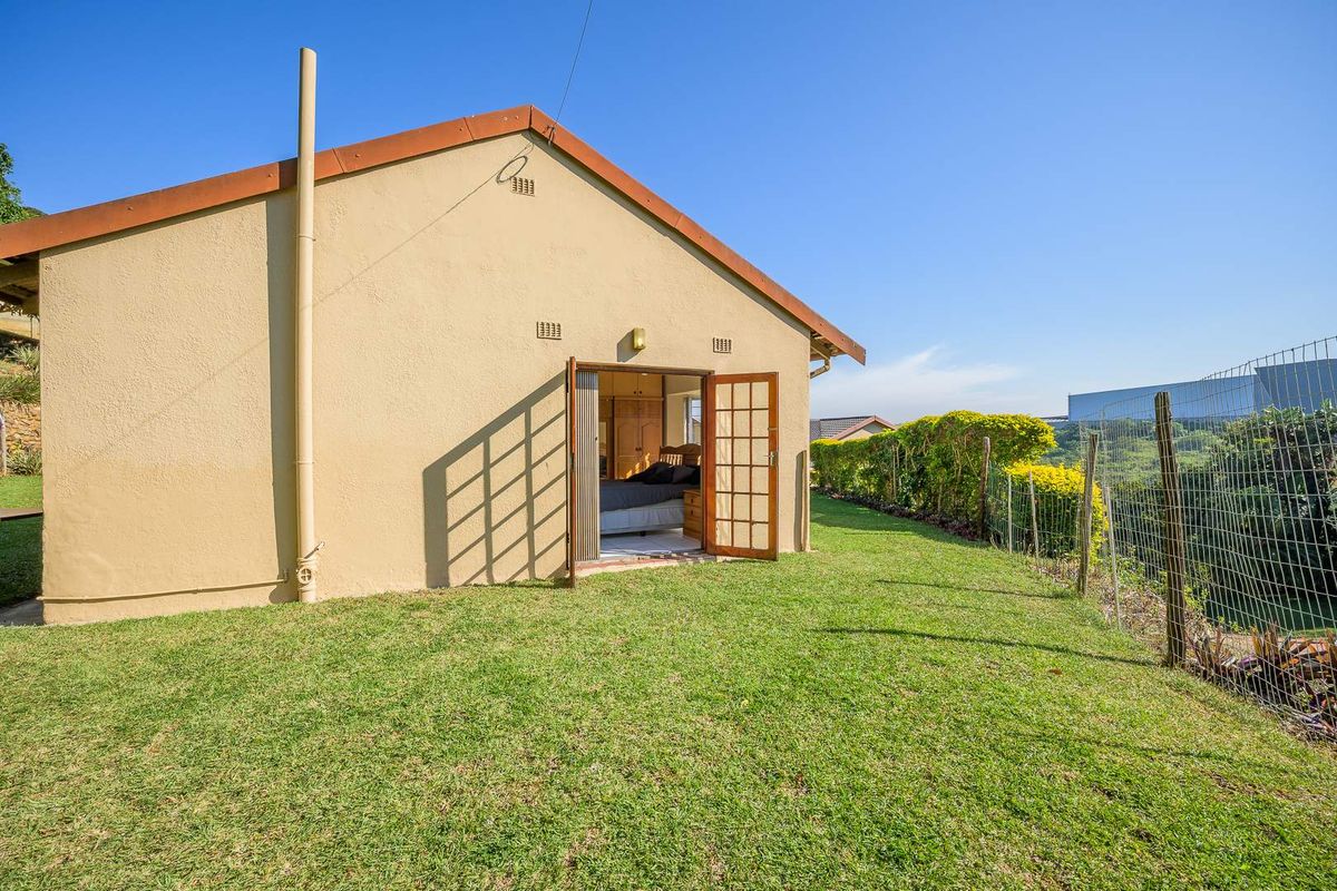 Rear view of the property featuring a lawn, wire perimeter fencing, and direct access to the interior through double doors.