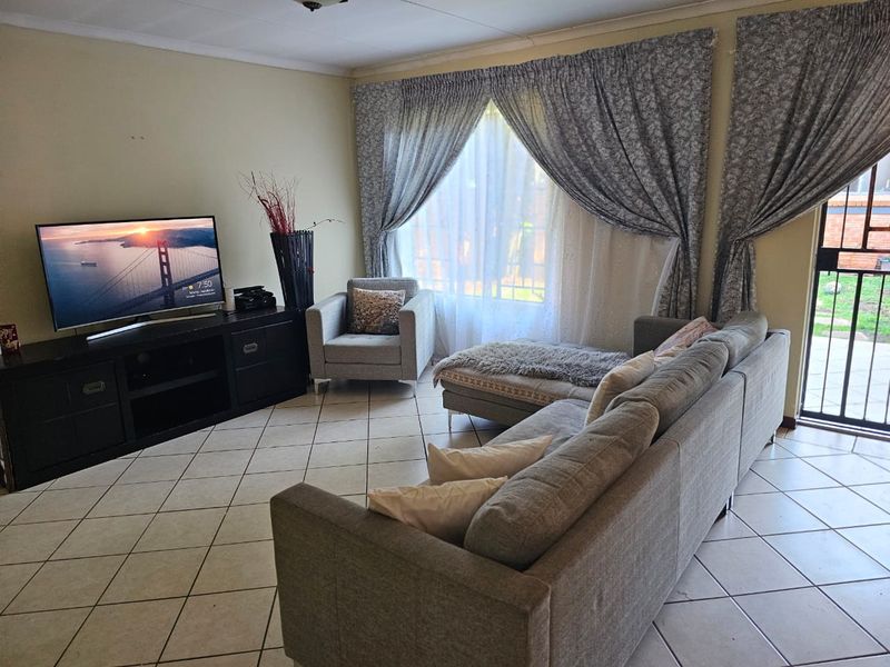 A comfortable living room featuring tiled flooring and a sliding glass door providing access to the exterior.