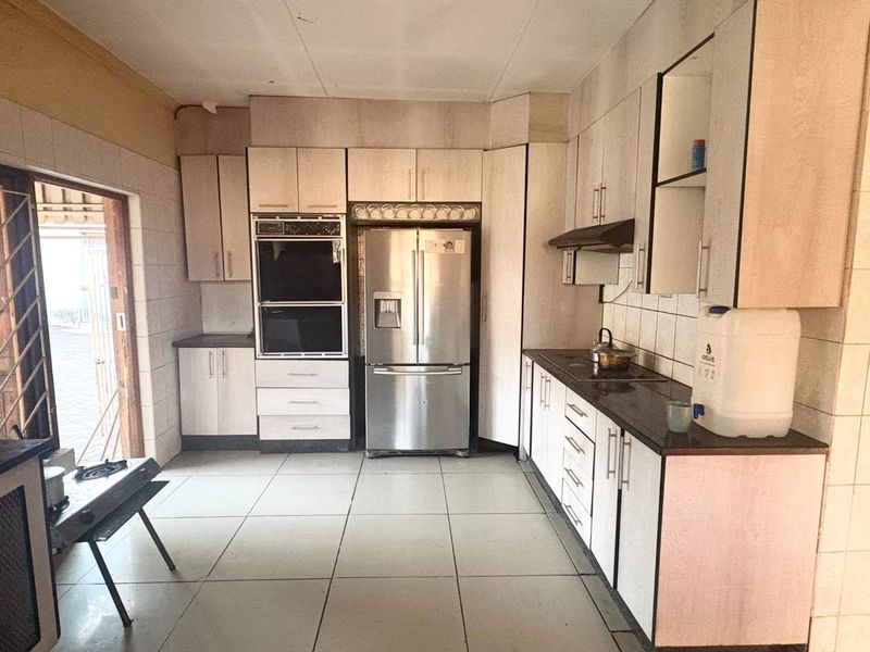 A functional kitchen featuring built-in cabinetry, granite countertops, a double oven, and tiled flooring with direct access to an outdoor area.