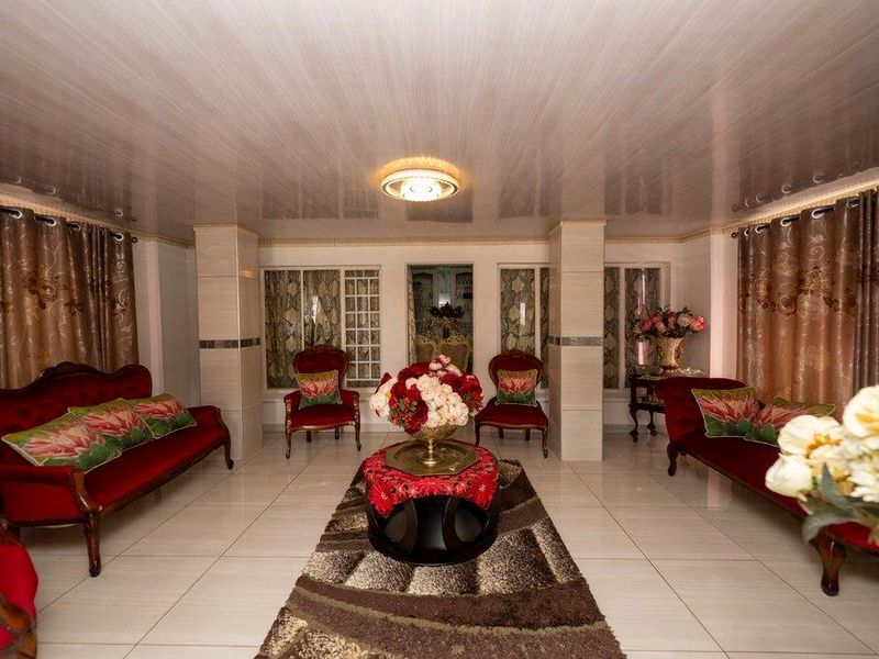 Spacious living room featuring tiled flooring, structural columns, and a recessed ceiling design, offering a formal layout with ample natural light.