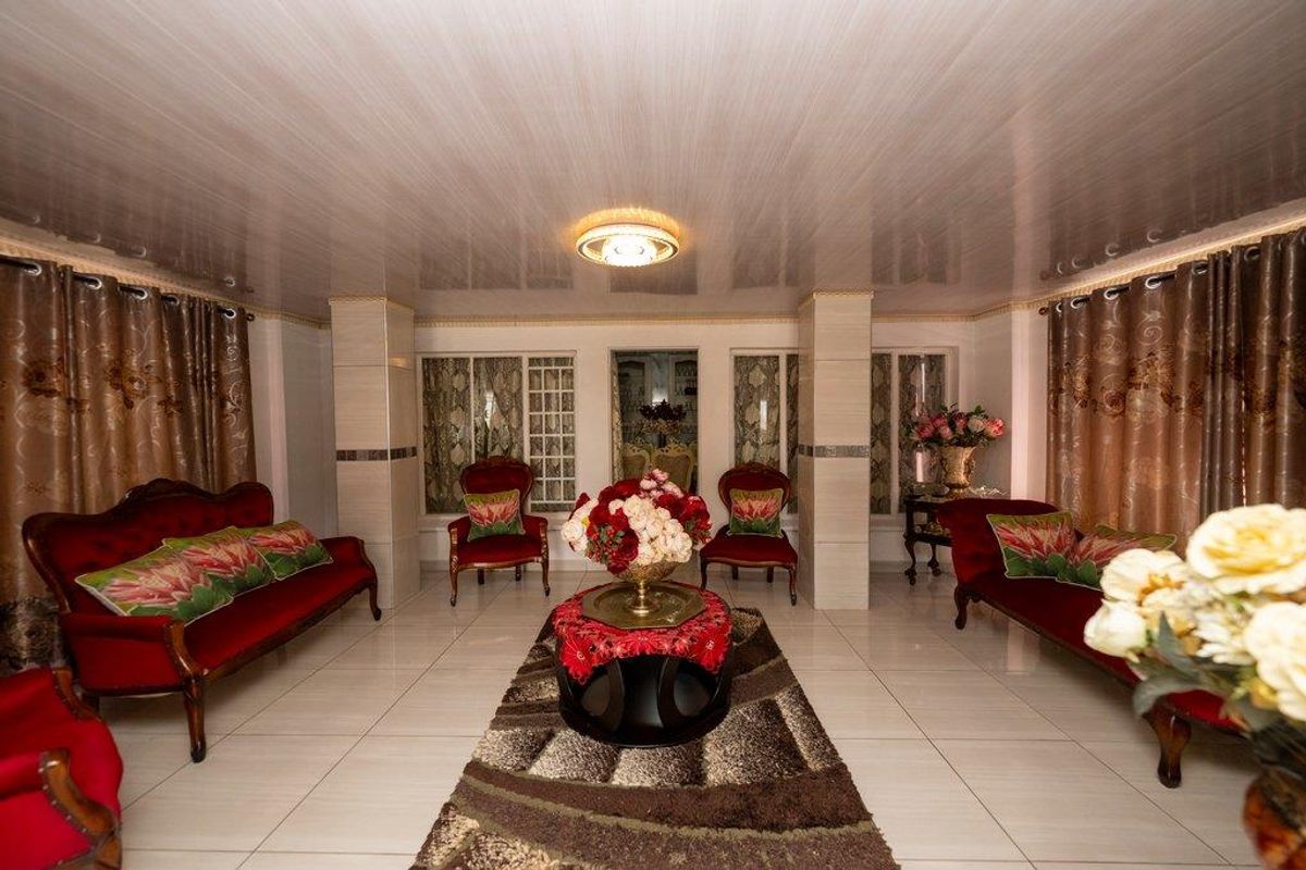 Spacious living room featuring tiled flooring, structural columns, and a recessed ceiling design, offering a formal layout with ample natural light.