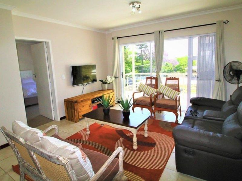 A comfortable living room featuring tiled flooring and a large sliding glass door that provides access to an outdoor balcony area.