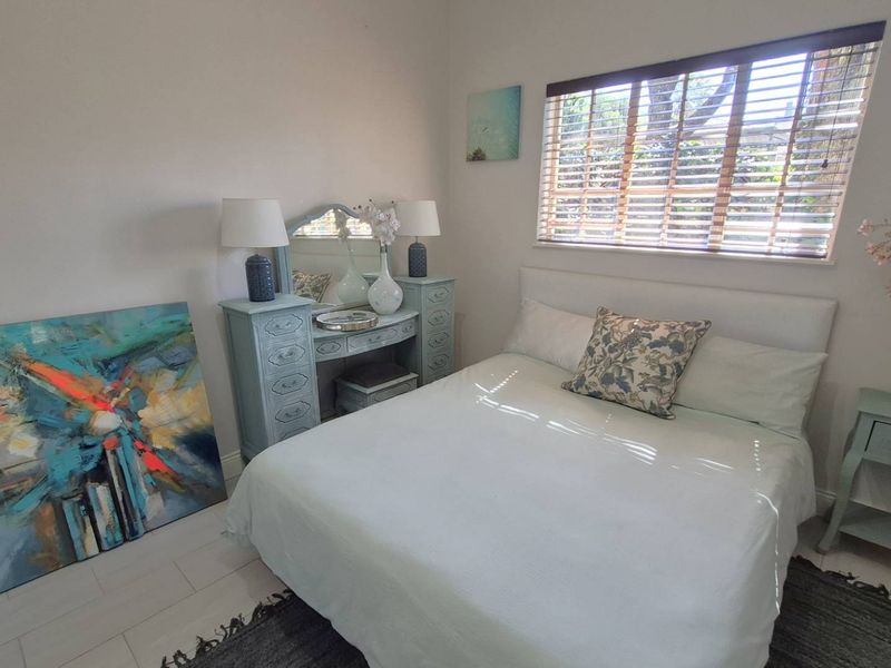 A well-lit bedroom featuring tiled flooring and venetian blinds, providing a comfortable and functional sleeping space.