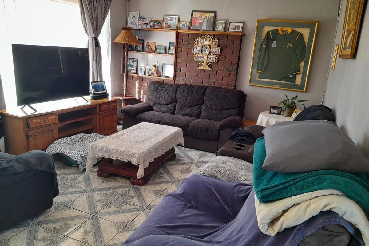 A living room featuring a brick feature wall with built-in shelving and tiled flooring.