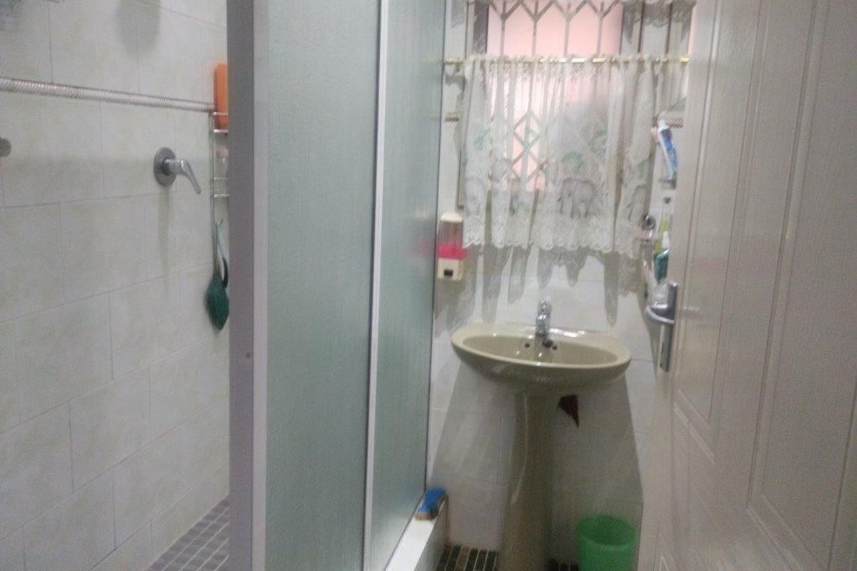 A compact bathroom featuring a pedestal basin and a separate shower enclosure with tiled finishes.