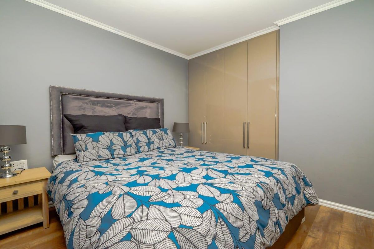 A well-maintained bedroom featuring built-in high-gloss cabinetry and durable wood-look flooring, offering a clean and functional living space.