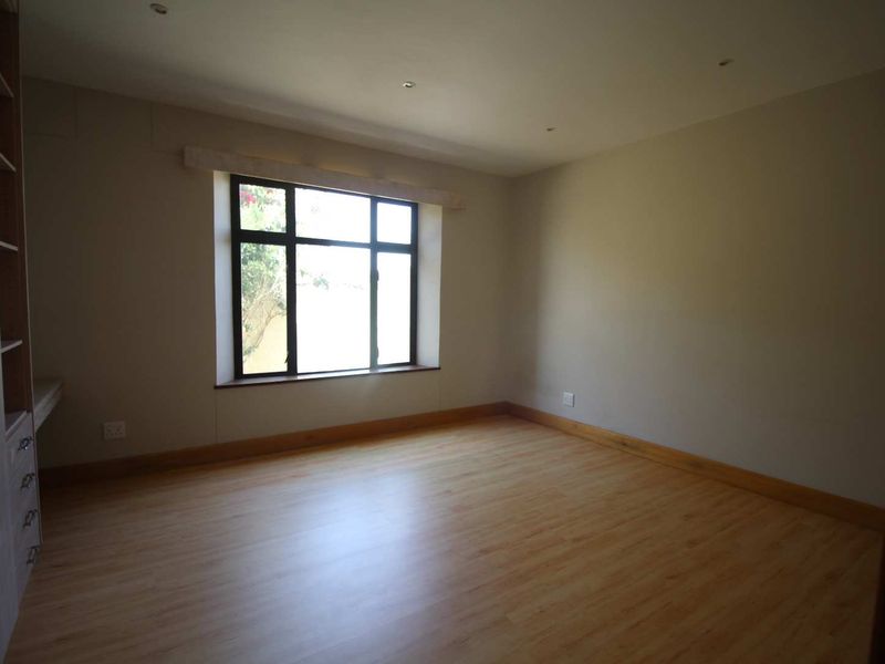 A bright, empty bedroom featuring laminate flooring, recessed lighting, and built-in cabinetry, offering a clean and neutral space ready for personalization.