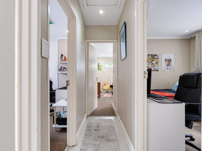 A functional hallway providing access to multiple rooms, featuring neutral wall finishes, recessed lighting, and standard internal door frames.