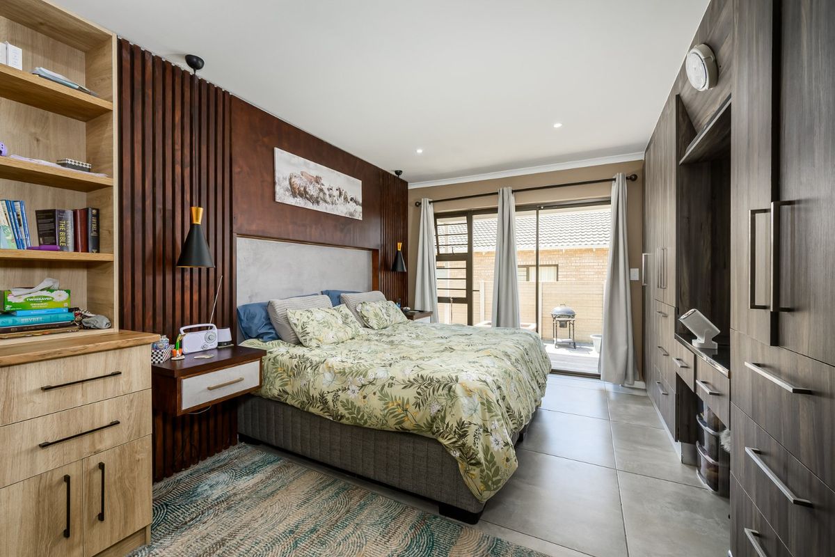 A well-appointed bedroom featuring custom built-in cabinetry, a stylish slatted timber feature wall, and direct access to an outdoor patio area.
