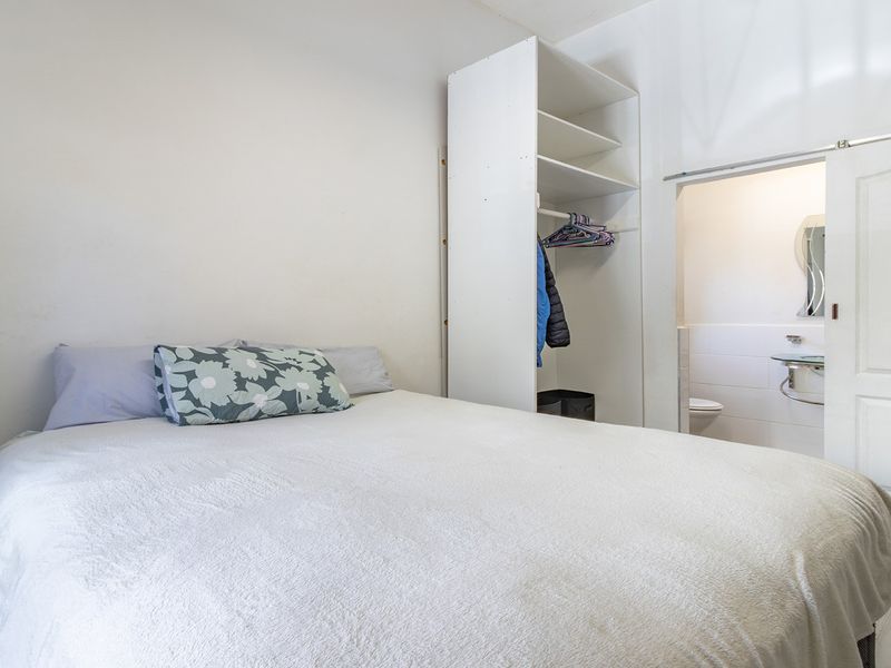 A functional bedroom featuring a built-in wardrobe and direct access to an en-suite bathroom through a sliding door.
